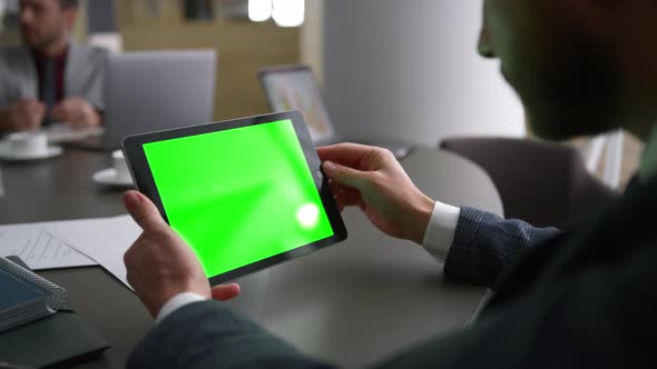 Businessman Using Tablet Device Green Screen Looking Corporate News in Workplace