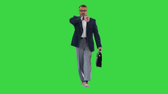 Mature Businessman Walking in a Hurry and Looking at Watch on a Green Screen, Chroma Key