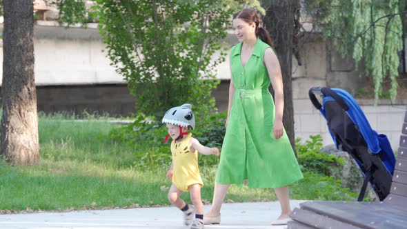 Mother Teaches Her Toddler to Ride Balance Bike for Younger Kids Outdoors 1