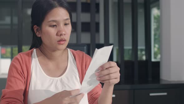 Asian Pregnant woman records of income and expenses worried, serious, stress while record budget
