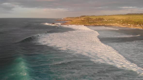 Surfers wait for the perfect wave and waves roll in to Maui Hawaii's Ho'okipa Beach at sunset.