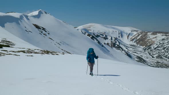 Woman with a Backpack Travels in the Mountains in Winter