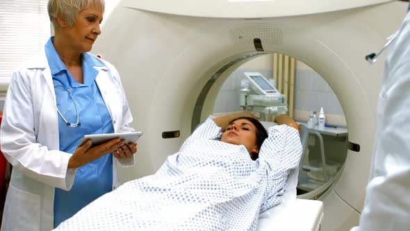 Doctor reviewing chart of female patient on digital tablet before mri scan