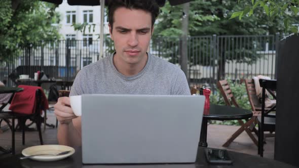 Man Drinking Coffee and Working on Laptop While Sitting in Cafe Terrace