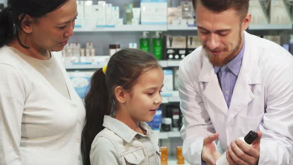 Friendly Pharmacist Shows Little Girl One of the Tubes