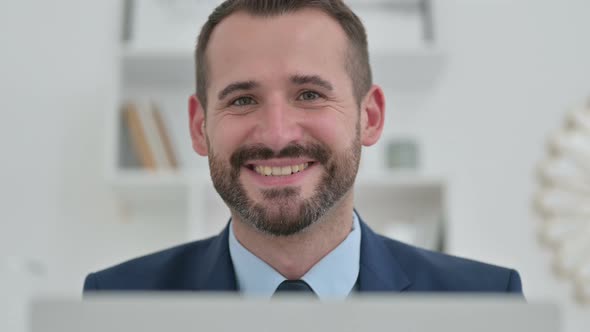 Businessman with Laptop Smiling at the Camera