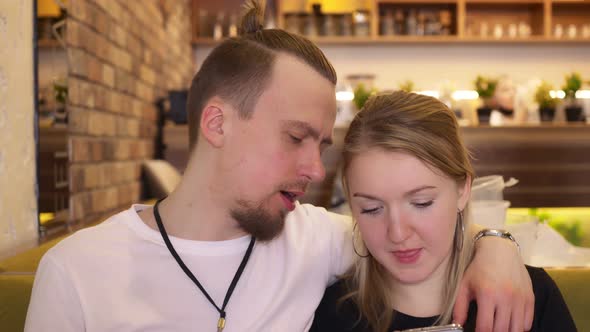 In a Restaurant a Young Man with a Young Woman Spend Their Leisure Time Sitting on a Sofa Talking to