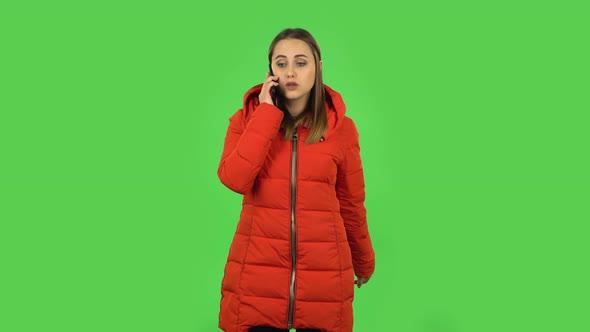 Lovely Girl in a Red Down Jacket Is Talking for Mobile Phone. Green Screen