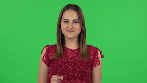 Portrait of Tender Girl in Red Dress Is Smiling and Showing Heart with Fingers Then Blowing Kiss