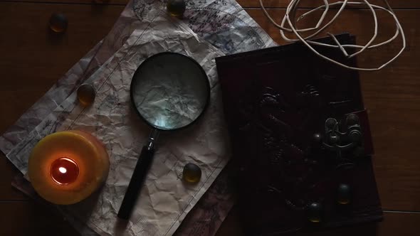 beautiful vintage background with ancient maps, a book, a candle some stones and a magnifying glass