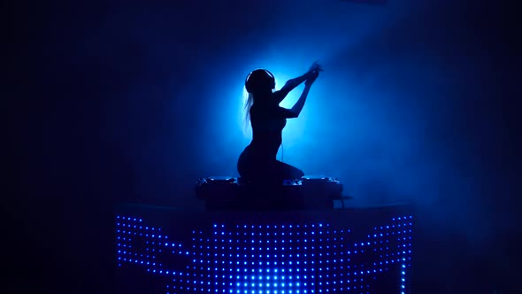 Silhouette of Sexy DJ Girl Dancing Behind the Decks
