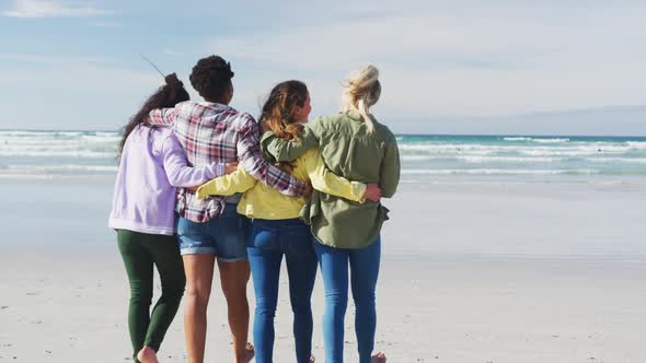 Happy group of diverse female friends having fun, walking along beach