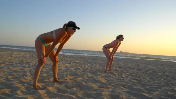 Women teams play beach volleyball at sunset and a player passes the ball.