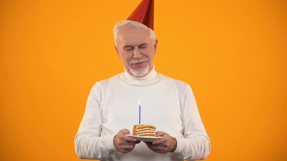 Cheerful Aged Man Blowing Birthday Cake Candle, Celebrating Holiday, Good Mood