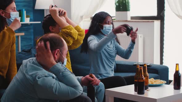 Multiethnic People Celebrate Game Victory in Living Room with Joystick