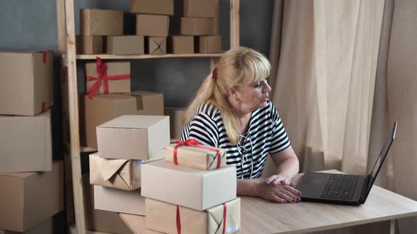 Mature Saleswoman Using Computer While Checking Orders in Ecommerce Clothing Store