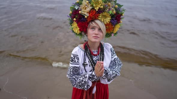 Young Ukrainian Woman Praying for Ukraine Standing on River Bank in Embroidered Dress and Head