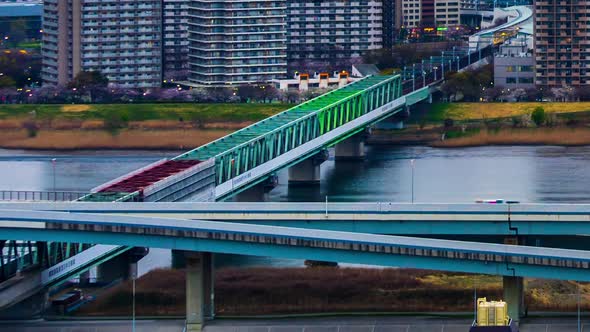 Day to night time lapse of train crossing Arakawa river on a railway bridge in Tokyo, Japan