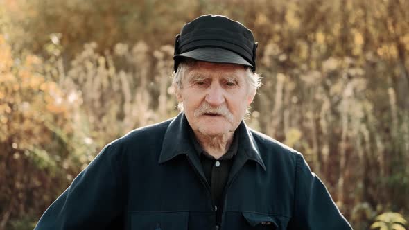 Close up portrait of wise old farmer looking to the camera in the sunny day