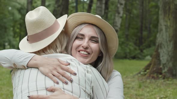 Two Blond-haired Women Embracing Outdoors