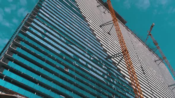 Crane on a Construction Site Against the Blue Sky Is Building New Skyscraper. Building Construction alt