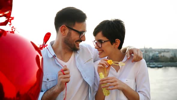 Romantic Young Couple Dating Outdoor and Blowing Bubbles