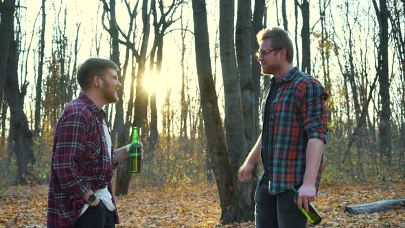 Cheerful Tourists Talking and Drinking Beer at Picnic in Forest