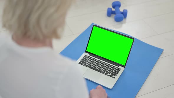 Rear View of Senior Old Woman Doing Yoga While Looking at Laptop with Chroma Key Screen