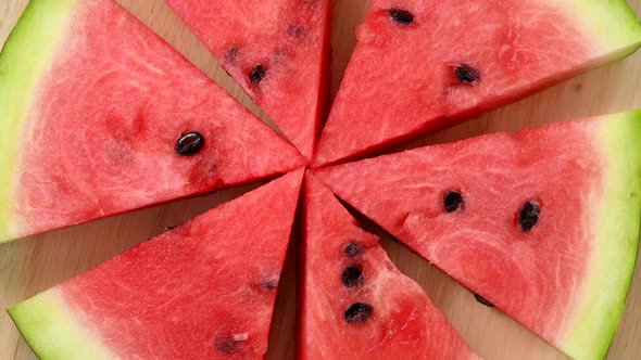 Slices of watermelon rotating top view on wooden background