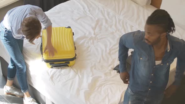 Top View of Young Interracial Couple Unpacking Luggage in Hotel Room or at Home. African American