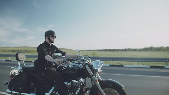 Motorcycle driver riding alone on asphalt motorway. Biker in the motion at the empty road