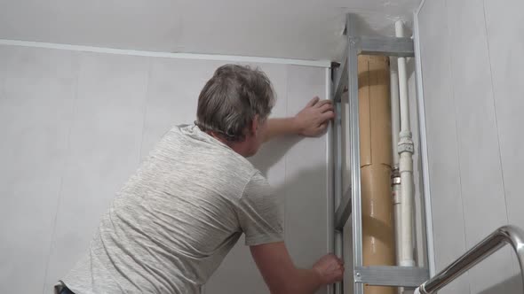 A Man Tries on a Plastic Corner When Installing PVC Panels in Bathroom