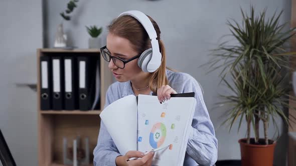 Young Woman in Earphones Having Conference Video Call with Somebody