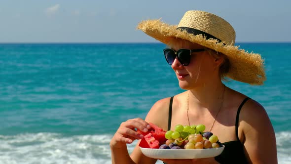 Woman on the Beach Eats Fruit