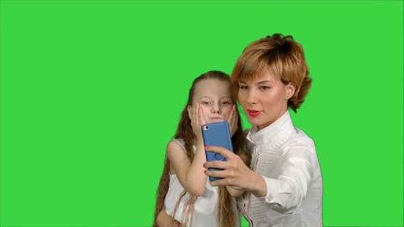 Cute Family Mother with Child Daughter Taking Selfie Smart Phone Photo on a Green Screen, Chroma Key