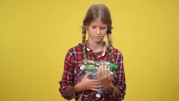 Concentrated Serious Teenage Girl Looking at Camera Holding Used Plastic Bottles