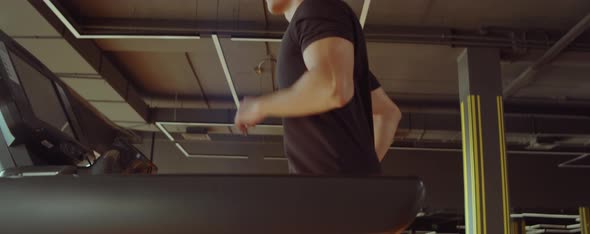 Athletic Man Running on Treadmill in Gym