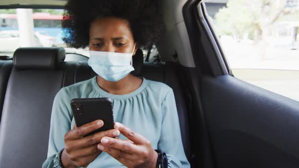 African american businesswoman with face mask using smartphone