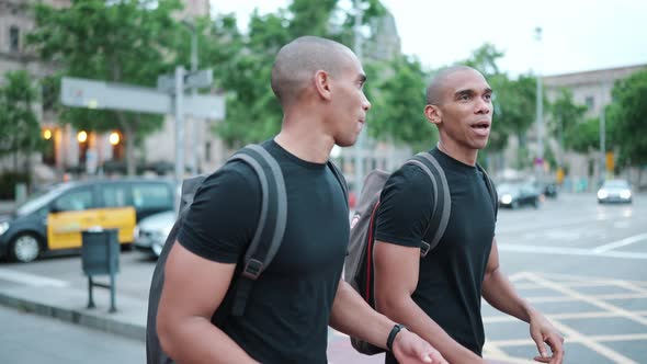 Two pretty bald African brothers talking and walking on the street