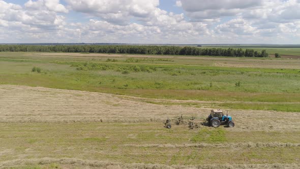 Tractor with Rake Tedders on the Farm Field