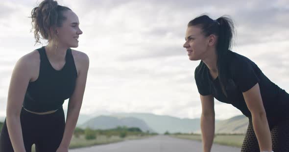 Two Women Rest After Running and Celebrate the Success of Training with a High Five