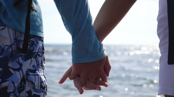 Young Pair Holding Hands of Each Other Standing on Ocean Coast. Couple of Lovers Resting on Resort