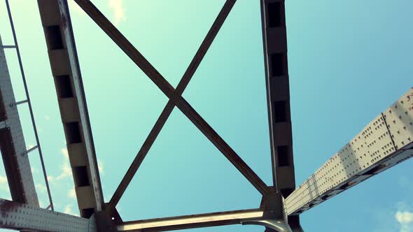 Iron Construction of Bridge Against Blue Sky with White Clouds. Driving Under Bridge, View of Bridge