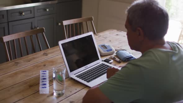 Senior mixed race man having online medical consultation using laptop