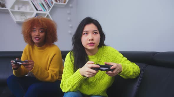 Focused Competitive Lesbian Couple Play Games at Home, Asian and African American Females Having