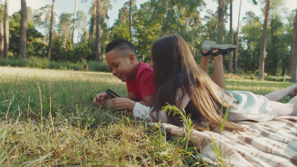 School Kids Using Magnifying Glass Looking at Herbs and Bugs Outdoors