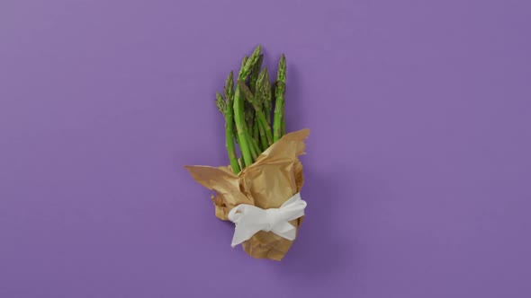 Video of fresh asparagus wrapped with white ribbon and copy space over lilac background