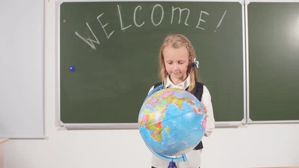 School Girl with Globe in Classroom Chalkboard on Background