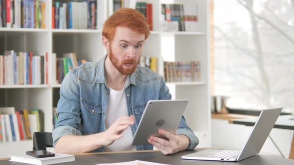 Casual Redhead Man Celebrating Success on Tablet