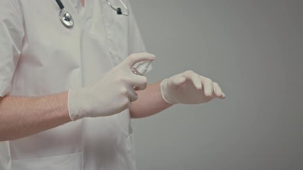 Doctors Gloved Hands He Sprays Antiseptic On His Hands And Rubs Liquid